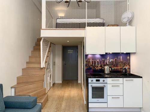 uma cozinha com armários brancos e uma escada numa casa em Orange Apartments Mere em Talin