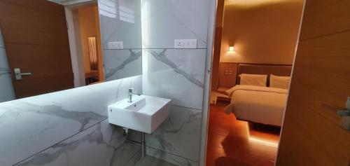een badkamer met een wastafel, een spiegel en een bed bij The Nisha Continental in Kottayam