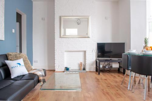 a living room with a black couch and a tv at Bedford Rd Apartment Ideal for Hospital & Town Centre in Kempston