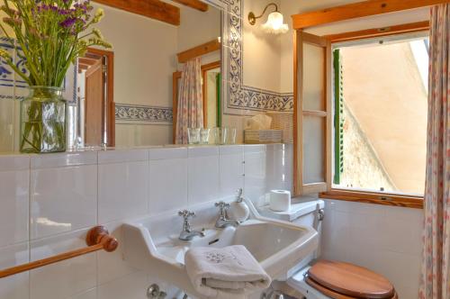 baño con lavabo y aseo y ventana en Can Busquets, en Banyalbufar