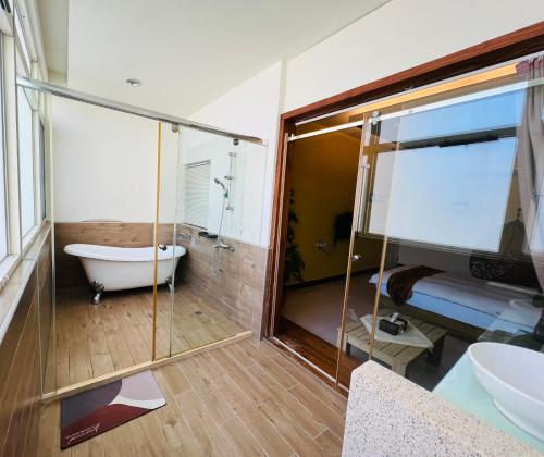 a bathroom with a tub and a glass wall at 秋合民宿 in Hualien City