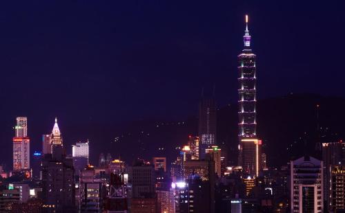 a city skyline at night with a tall building at urban abode apartments in Taipei