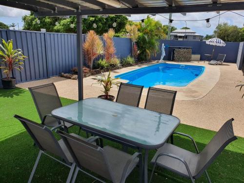 a table and chairs in front of a swimming pool at Sun City Motel in Bundaberg