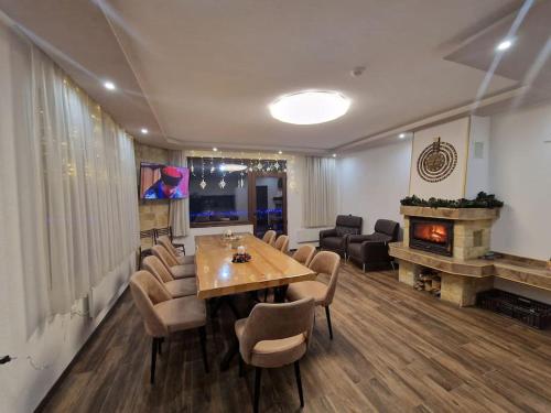a dining room with a table and a fireplace at Къща за гости "СЛАВЕНА" in Dospat