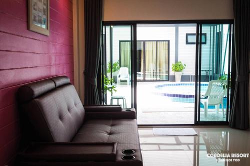 a couch in a living room with a pink wall at Cordelia Resort Sam Roi Yot in Sam Roi Yot