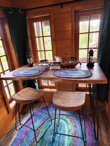 a wooden table with three stools in a room with windows at The Eagle's Nest Treehouse Cabin in Palmer