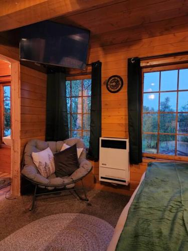 a room with a chair and a television in a cabin at The Eagle's Nest Treehouse Cabin in Palmer