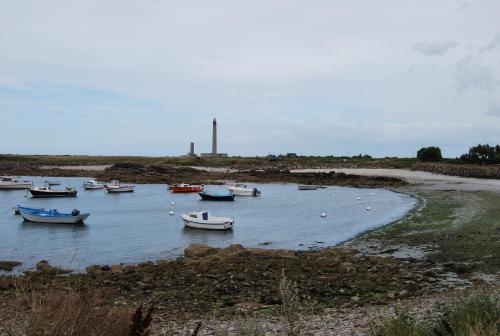 a group of boats in a body of water with a lighthouse at Hotel Logis Au Moyne de Saire in Réville