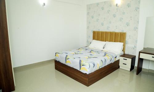 a bedroom with a bed with a wooden frame and a desk at Alite Enclaves Fully furnished apartments in Trichūr