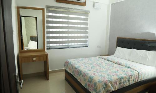 a bedroom with a bed and a mirror and a window at Alite Enclaves Fully furnished apartments in Trichūr