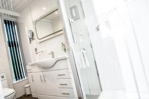 a white bathroom with a sink and a shower at Eildon Guest House in Inverness