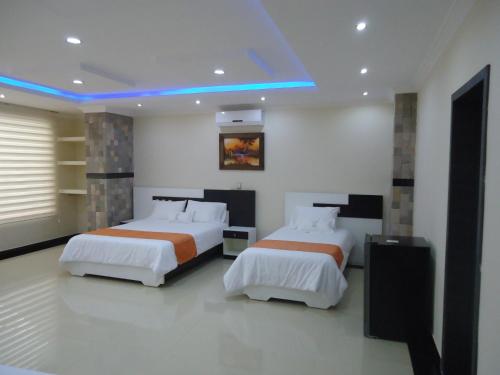1 dormitorio con 2 camas y luz azul en Hotel Joya de la Selva, en Tena