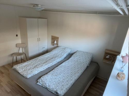 a bedroom with two beds and a chair at Hyggelig & lys kælderlejlighed in Herning
