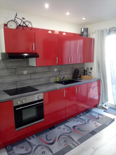 - une cuisine rouge avec un évier et des placards rouges dans l'établissement Au p'tit bonheur, à Saint-Rambert-dʼAlbon