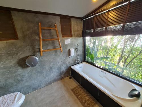a bathroom with a bath tub and a window at Naga Tara Boutique Resort in Phayao