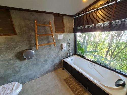 un bagno con vasca e finestra di Naga Tara Boutique Resort a Phayao