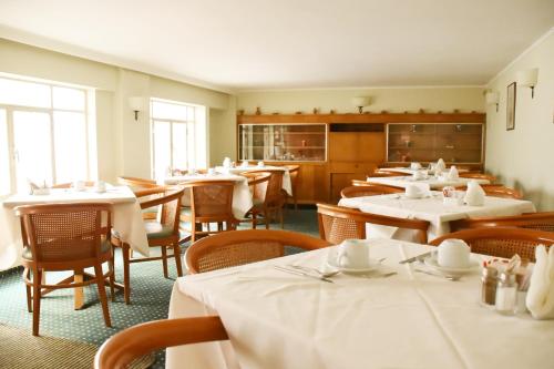 uma sala de jantar com mesas e cadeiras com toalha de mesa branca em Adrian Hotel em Atenas