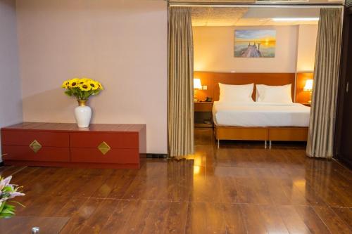 1 dormitorio con 1 cama y un jarrón de flores sobre una mesa en Three 888 Hotel en Dubái