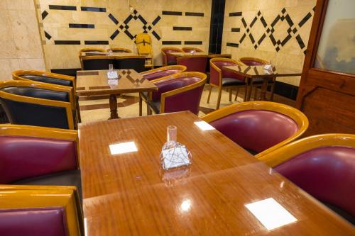 Un comedor con mesas de madera y sillas moradas. en Three 888 Hotel, en Dubái