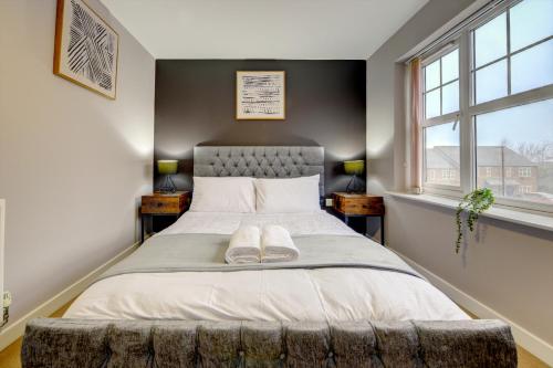 a bedroom with a large bed with two windows at Tudor Close in Sheffield