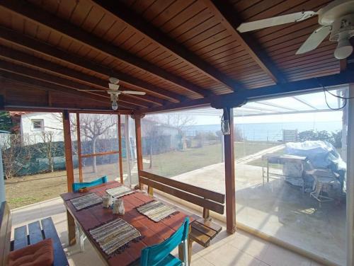 a screened in porch with a table and a ceiling fan at 7ο_seahome in Alexandroupoli