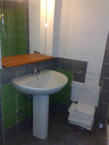 a bathroom with a sink and green tiled walls at La Locanda Di Cadì in Petralia Soprana