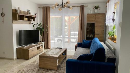 uma sala de estar com um sofá azul e uma televisão em Dom z plażą Świerkowa Przystań em Giżycko