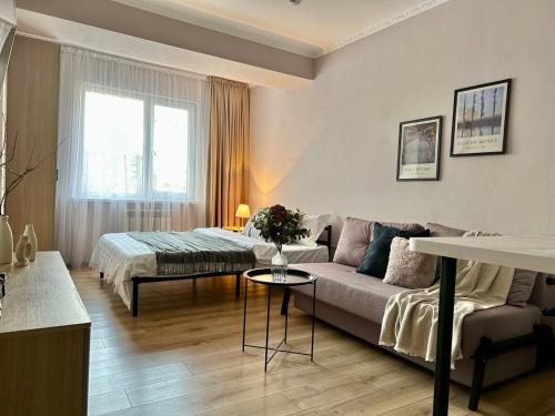 a living room with a couch and a bed at Студия МЕРЕНГА в центре Алматы in Almaty