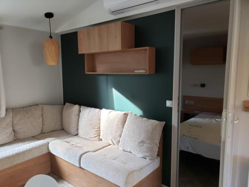 a living room with a couch and a bedroom at CAMPING SIBLU LA CARRABASSE MOBIL HOME OL21 in Vias