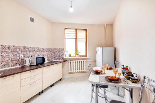 a small kitchen with a table and a refrigerator at Просторные апартаменты в ЖК 7 бочек in Taldykolʼ