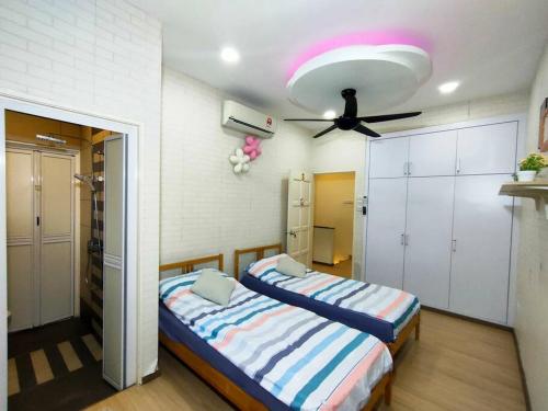 a bedroom with two beds and a ceiling fan at 678 homestay 4 room 5 minutes to tower in Teluk Intan