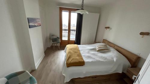 een slaapkamer met een bed met witte lakens en een raam bij Appartement lumineux au centre du village in Leysin