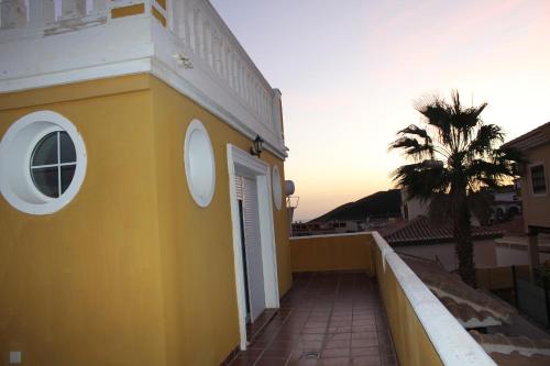 a yellow building with a white door and a palm tree at Villa Granada Motril in Motril