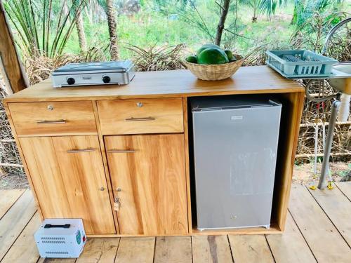 eine Holztheke mit einem Kühlschrank und einem Obstkorb in der Unterkunft Glamping Lakeview Ouidah 