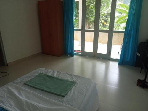 ein Schlafzimmer mit einem Bett mit einem grünen Handtuch darauf in der Unterkunft Hemali in Galle