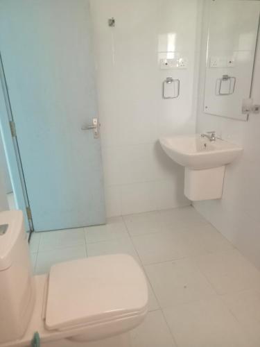 ein weißes Bad mit einem WC und einem Waschbecken in der Unterkunft Hemali in Galle