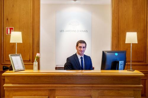 un homme assis à un bureau avec un ordinateur dans l'établissement Les Jardins d'Anaïs, à Luxembourg