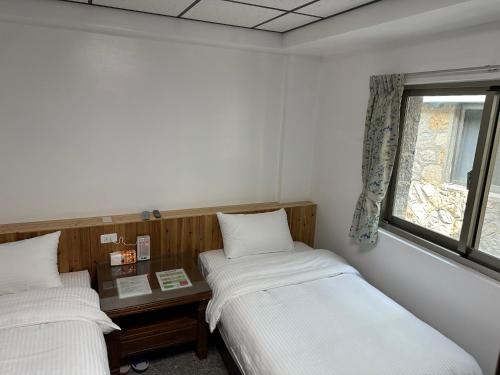 two beds in a room with a window at 雲台客棧民宿 in Nangan
