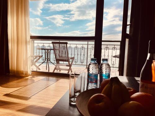 een tafel met een fruitschaal en flessen water op een balkon bij At the American's Hotel in Pomorie