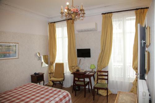 a bedroom with a bed and a desk and a television at Hotel Cronstadt in Nice