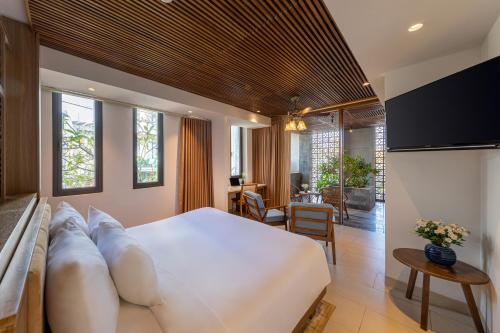 a bedroom with a large white bed and a living room at Daisy Boutique Hotel in Da Nang