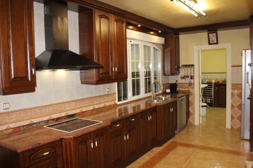 a kitchen with wooden cabinets and a black hood at Villa Granada Motril in Motril
