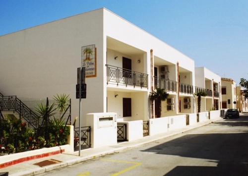 a white building with balconies on the side of a street at Le Palme Di Conturrana in San Vito lo Capo