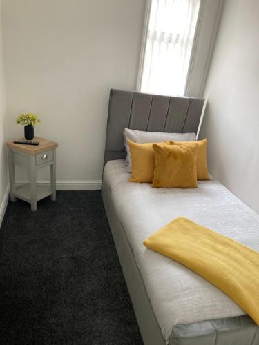 Un dormitorio con una cama con almohadas amarillas y una ventana en Cheshire Home Stays, en Church Coppenhall