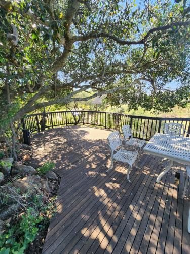 a wooden deck with a table and chairs under a tree at Milkwood Safari Lodge in Warmbaths