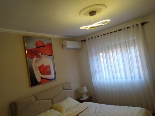 ein Schlafzimmer mit einem Bild einer Frau mit Hut in der Unterkunft Dolce Casa in Korçë