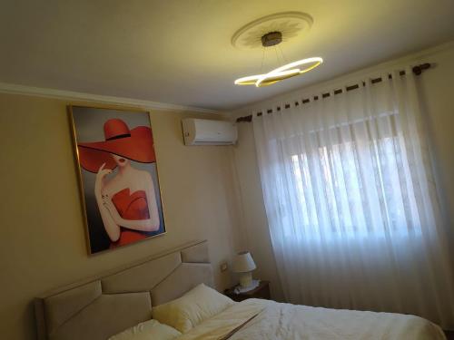 a bedroom with a painting of a woman in a hat at Dolce Casa in Korçë