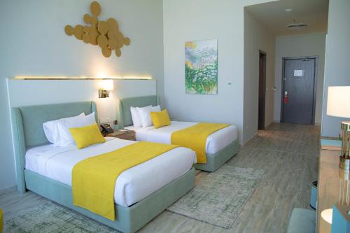 two beds in a hotel room with yellow and white at Tolip Olympic International City in New cairo