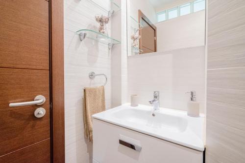 Baño blanco con lavabo y espejo en Mare Home - Beach & City, en Las Palmas de Gran Canaria