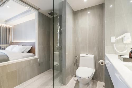 a bathroom with a toilet and a glass shower at Shambhala Hotel Pattaya in Pattaya Central